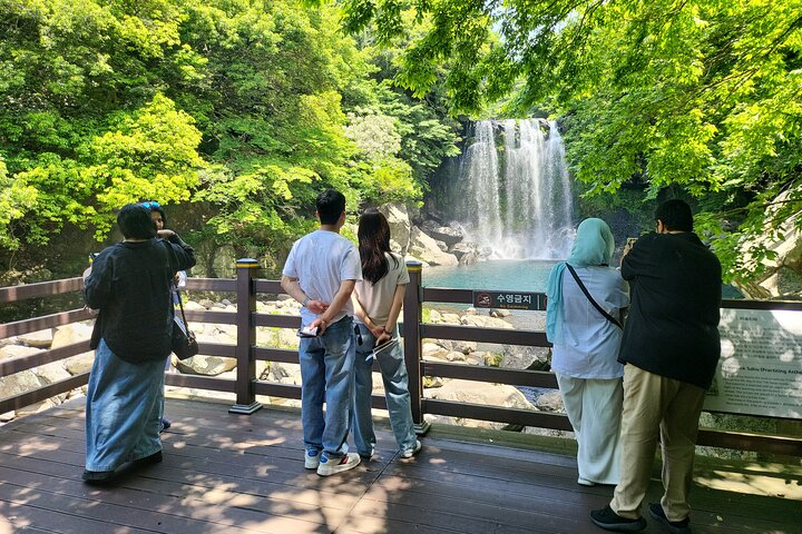 Discover the serene beauty of Cheonjeyeon Falls where lush greenery embraces cascading waters inviting moments of reflection and connection with nature's wonders. A perfect escape in Jeju Island.